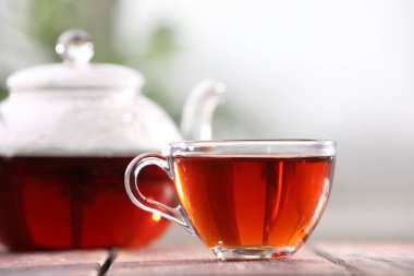Cam bardakta Aromatik çay ve masa üzerinde çaydanlık bulanık arka plan, yakın plan