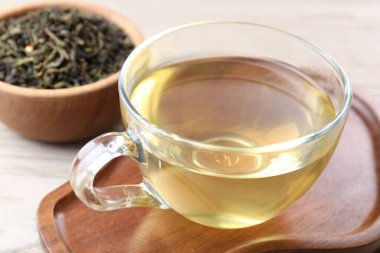 Yeşil çay ve kuru yapraklar hafif ahşap masada, yakın plan