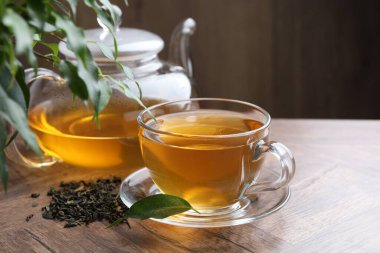 Taze yeşil çay ve ahşap masada kuru yapraklar.