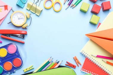 Farklı okul malzemelerinin çerçevesi ve açık mavi arka planda renkli ahşap küplerin düzlüğü. Metin için boşluk