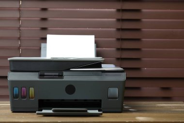 Kapalı alanda, ahşap masa üzerinde kağıt olan siyah bir yazıcı, yakın plan. Metin için boşluk