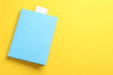 Sarı arka planda beyaz yer imli kitap, üst manzara. Metin için boşluk