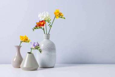 Beyaz masadaki vazoların içinde güzel frezya çiçekleri. Metin için boşluk