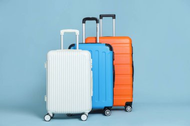 Açık mavi arka planda üç farklı şık bavul.