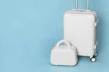 Açık mavi arka planda iki farklı şık bavul. Metin için boşluk