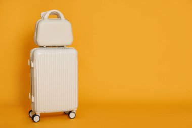 Turuncu arkaplanda farklı bavullar, metin için boşluk