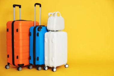 Turuncu arkaplanda farklı bavullar, metin için boşluk