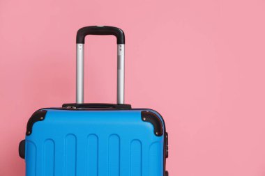 Pembe arka planda açık mavi bir bavul, yakın plan. Metin için boşluk