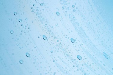 Açık mavi arkaplanda su damlaları, yakın plan