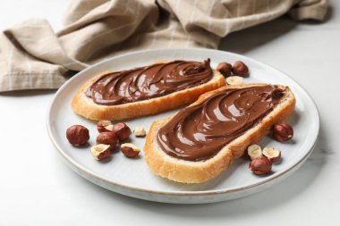 Çikolata ezmeli tostlar ve beyaz mermer masada fındıklar, yakın plan.