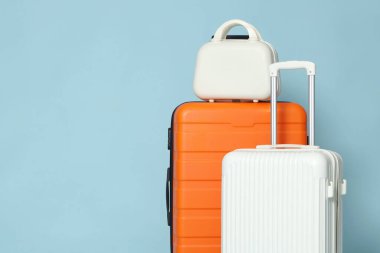 Açık mavi arka planda üç farklı şık bavul, yakın plan. Metin için boşluk