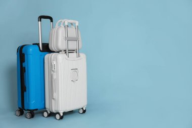 Three different stylish suitcases on light blue background, space for text