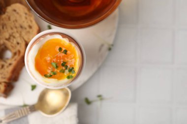 Yumuşak yumurta, mikro yeşillik, beyaz fayanslı masada ekmek ve çay ile nefis bir kahvaltı, üst manzara. Metin için boşluk