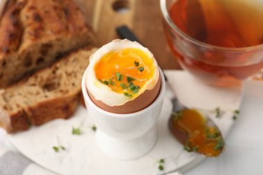 Yumuşak yumurta, mikro yeşiller, ekmek ve çay ile nefis bir kahvaltı, yakın plan.