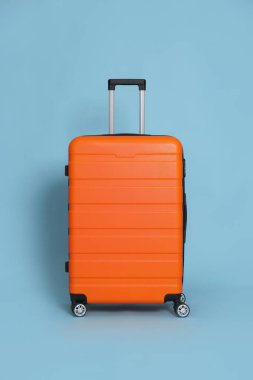 Açık mavi arkaplanda turuncu bir bavul