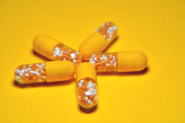 Capsules. Medical tablets, vitamins in granules, in yellow capsules on a yellow background. blur as a creative idea of the author, close-up, copy space