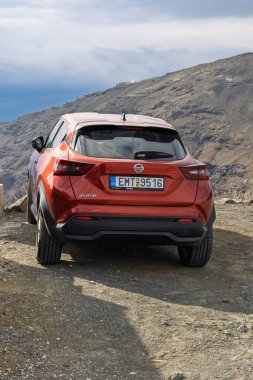 Orange Nissan Juke SUV Yunanistan 'ın Santorini kentindeki Volkanik Arazi üzerindeki Kirli Yol' a park etti