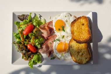 Lezzetli ve sağlıklı tüm gün kahvaltı tabağı kızarmış yumurta, pastırma, tost ve taze salata.