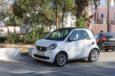 Beyaz Akıllı Fortwo mikro şehir arabası 5 Ekim 2025 'te Yunanistan, Santorini' de bir caddede park halinde.