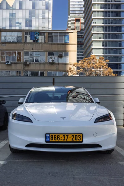 24 Aralık 2025 'te Ramat Gan, İsrail' e karşı şehir otoparkında park etmiş beyaz bir Tesla Model 3 Highland elektrikli arabasının ön görüntüsü.