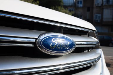 Beyaz bir arabanın gümüş radyatör ızgarasında mavi Ford amblemi, Givatayim, İsrail, 04 Aralık 2025