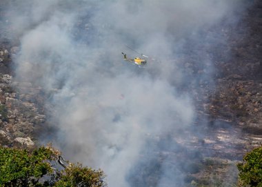 Bir itfaiye helikopteri Batı Burnu, Güney Afrika 'daki bir yangına su bırakıyor.