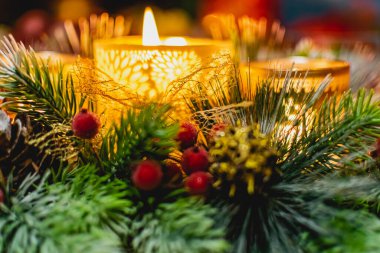 Yeşil ladin dalları arasında üç mum ve ışık ve altın külahlı kırmızı buzlu böğürtlenlerle güzel bir yeni yıl mumu tutucusu. Sıcak ve rahat dekorasyon.