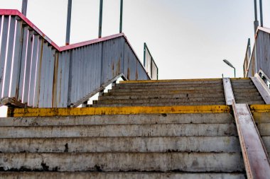 Her iki tarafında metal parmaklıklar olan kirli, çiğnenmiş beton merdivenler. Yürümek için eski bir yapı. Sokaktaki açık havada yükselen ve alçalan..
