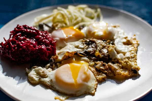 Fried eggs with mushrooms, long cheese noodles and beetroot caviar, a hearty fried dish for Breakfast with appetizers. The flowing liquid yellow egg yolk — Stock Image Fried Eggs Mushrooms Long Cheese Noodles Beetroot Caviar Hearty Fried Stock Photo