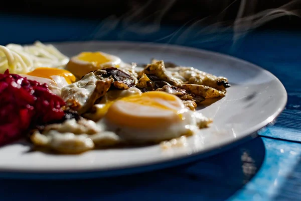 Fried eggs with mushrooms, long cheese noodles and beetroot caviar, a hearty fried dish for Breakfast with appetizers. The flowing liquid yellow egg yolk — Stock Image Fried Eggs Mushrooms Long Cheese Noodles Beetroot Caviar Hearty Fried Stock Photo