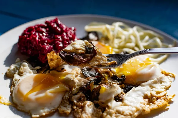 Fried eggs with mushrooms, long cheese noodles and beetroot caviar, a hearty fried dish for Breakfast with appetizers. The flowing liquid yellow egg yolk — Stock Image Fried Eggs Mushrooms Long Cheese Noodles Beetroot Caviar Hearty Fried Stock Photo