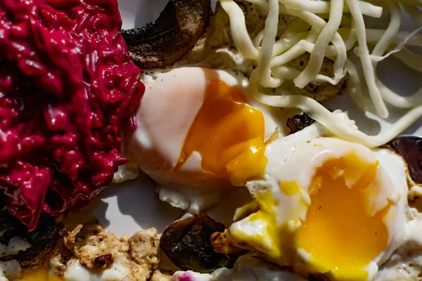 Fried eggs with mushrooms, long cheese noodles and beetroot caviar, a hearty fried dish for Breakfast with appetizers. The flowing liquid yellow egg yolk — Stock Image Fried Eggs Mushrooms Long Cheese Noodles Beetroot Caviar Hearty Fried Stock Picture