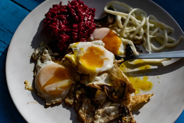Fried eggs with mushrooms, long cheese noodles and beetroot caviar, a hearty fried dish for Breakfast with appetizers. The flowing liquid yellow egg yolk — Stock Image Fried Eggs Mushrooms Long Cheese Noodles Beetroot Caviar Hearty Fried Royalty Free Stock Images