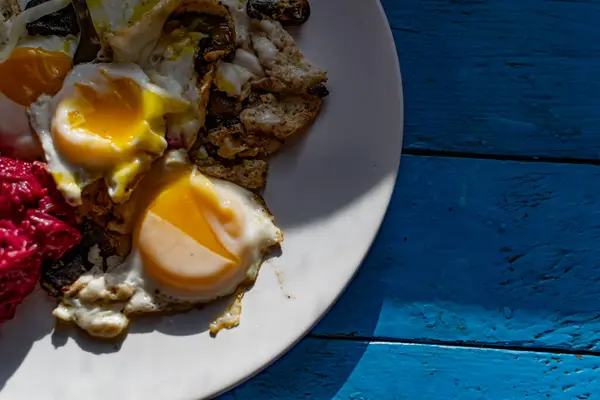 Fried eggs with mushrooms, long cheese noodles and beetroot caviar, a hearty fried dish for Breakfast with appetizers. The flowing liquid yellow egg yolk — Stock Image Fried Eggs Mushrooms Long Cheese Noodles Beetroot Caviar Hearty Fried Stock Image