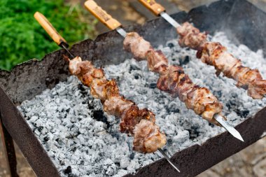 Ağız sulandıran domuz şişleri, kızarmış altın hamurlu ve dumanlı. Bahçede kömürlü barbekü ve şişte pişmiş et.