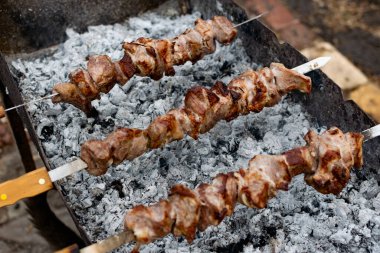 Ağız sulandıran domuz şişleri, kızarmış altın hamurlu ve dumanlı. Bahçede kömürlü barbekü ve şişte pişmiş et.
