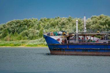 Nehirde yüzen ve Rostov bölgesinde yük taşıyan seyyar renk mavnası. Don nehrinde yaz mevsimi ve yanından geçen boyalı metalden yapılmış büyük ve uzun gemiler.