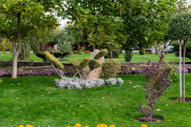 İlginç şekilli tuhaf bir çalılık, yapraklı kırpılmış yeşil dallardan yapılmış büyük pençeler gibi. Çiçekler, bitki örtüsü ve doğal çimenler arasında uzun tahta gövdeler üzerinde