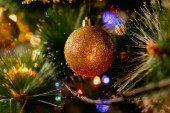 Zlaté vánoční ozdoby na zeleném umělém vánočním stromečku. Děláme slavnostní Vánoce. Vtipné roztomilé hračky a dárky na větvích