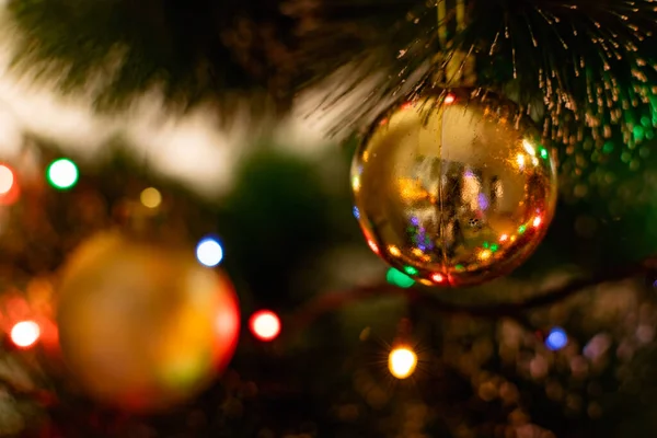 Yeşil bir yapay Noel ağacında altın Noel süslemeleri. Noel 'i kutluyoruz. Komik oyuncaklar ve dallarda hediyeler