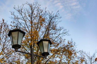 Açık gökyüzünün altında basit sokak ışıkları. Siyah metal çerçeve ve tozlu beyaz ampullü cam.