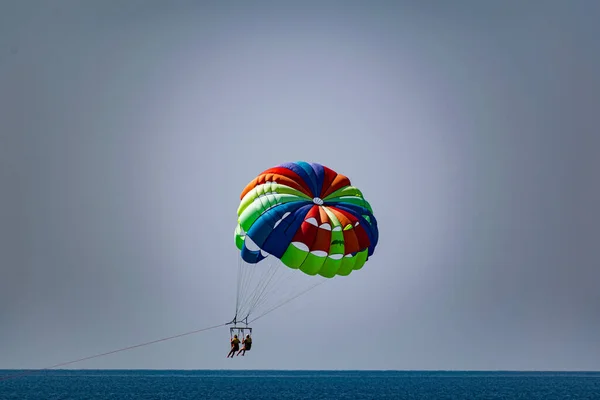 Rainbow Colored Striped Parachute Two Passengers People Flying Blue Sea — Stock Photo, Image