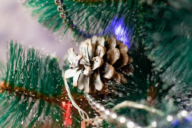 Noel ağacında ilginç Noel oyuncakları. Beyaz renkli Noel aksesuarları yanıp sönen fenerlerin ve ışıkların arasında. Aile tatilleri için şenlikli ve zarif şeyler..