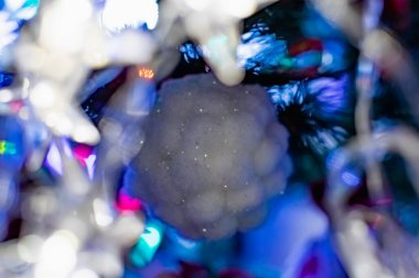 Noel ağacında ilginç Noel oyuncakları. Beyaz renkli Noel aksesuarları yanıp sönen fenerlerin ve ışıkların arasında. Aile tatilleri için şenlikli ve zarif şeyler..