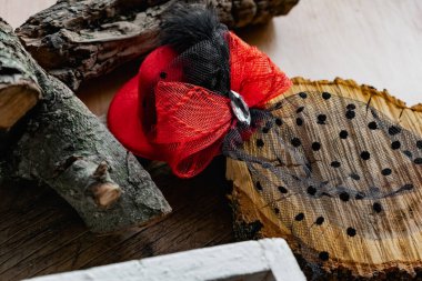 Kırmızı fiyonklu ve siyah peçeli bir saç tokasının üzerindeki dekoratif şapka. Temalı bir partiye suç ortaklığı ya da doğal bir ahşap arka planda tatil.