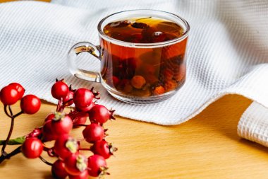 Şeffaf cam bardakta meyveli meyve ve böğürtlenlerden yapılmış meyve çayı. Sıcak içecek, beyaz havlunun üzerindeki taze gübre gibi.