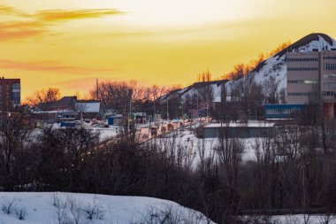 Açık bir günde gün batımında renkli gökyüzü çeşitli renklerle oynar, zıt ve zengin güzel dağ ve şehrin kışın parlaklığının görüntüsü.