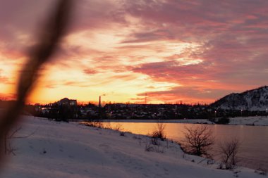 Açık bir günde gün batımında renkli gökyüzü çeşitli renklerle oynar, zıt ve zengin güzel dağ ve şehrin kışın parlaklığının görüntüsü.