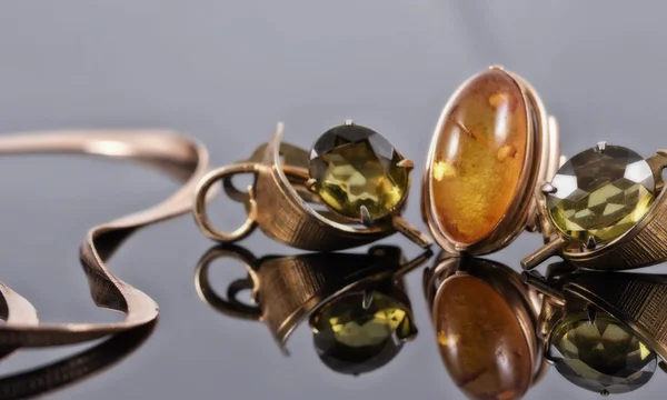 Pendientes antiguos de oro con piedras verdes y un anillo con ámbar — Foto de Stock