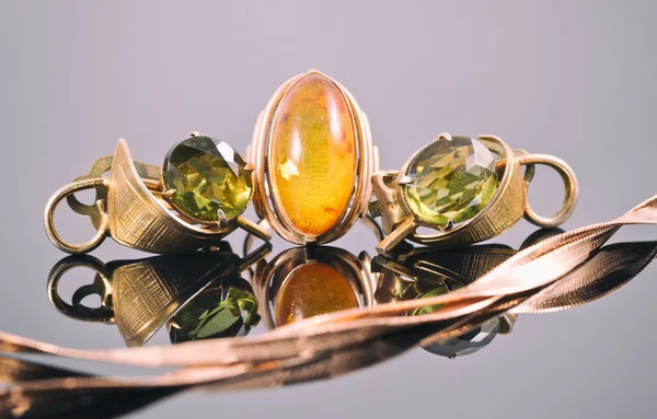 Alte goldene Ohrringe mit grünen Steinen und ein Ring mit Bernstein — Stockfoto